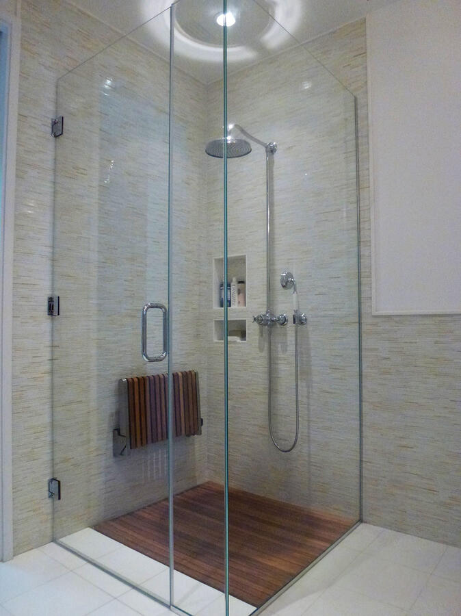 Bathroom stall with wooden paneled floors and a foldable wooden seat