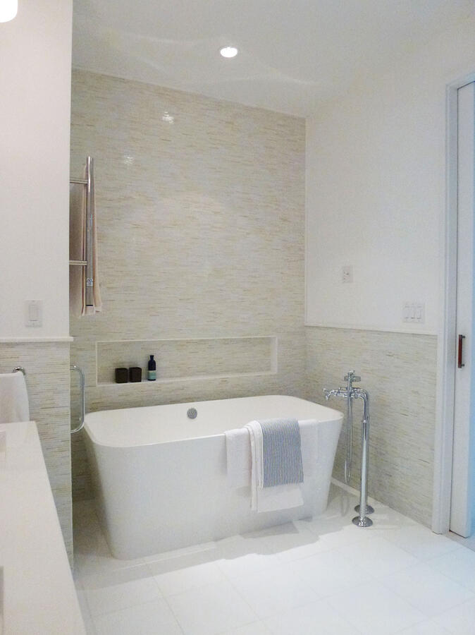 A white soaking bathtub in a brightly lit bathroom