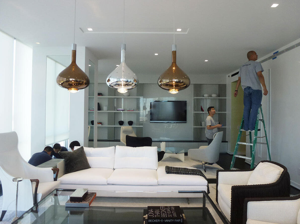 A room with a bookshelf to the far left and windows