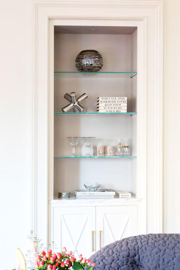 A room with a bookshelf to the far left and windows