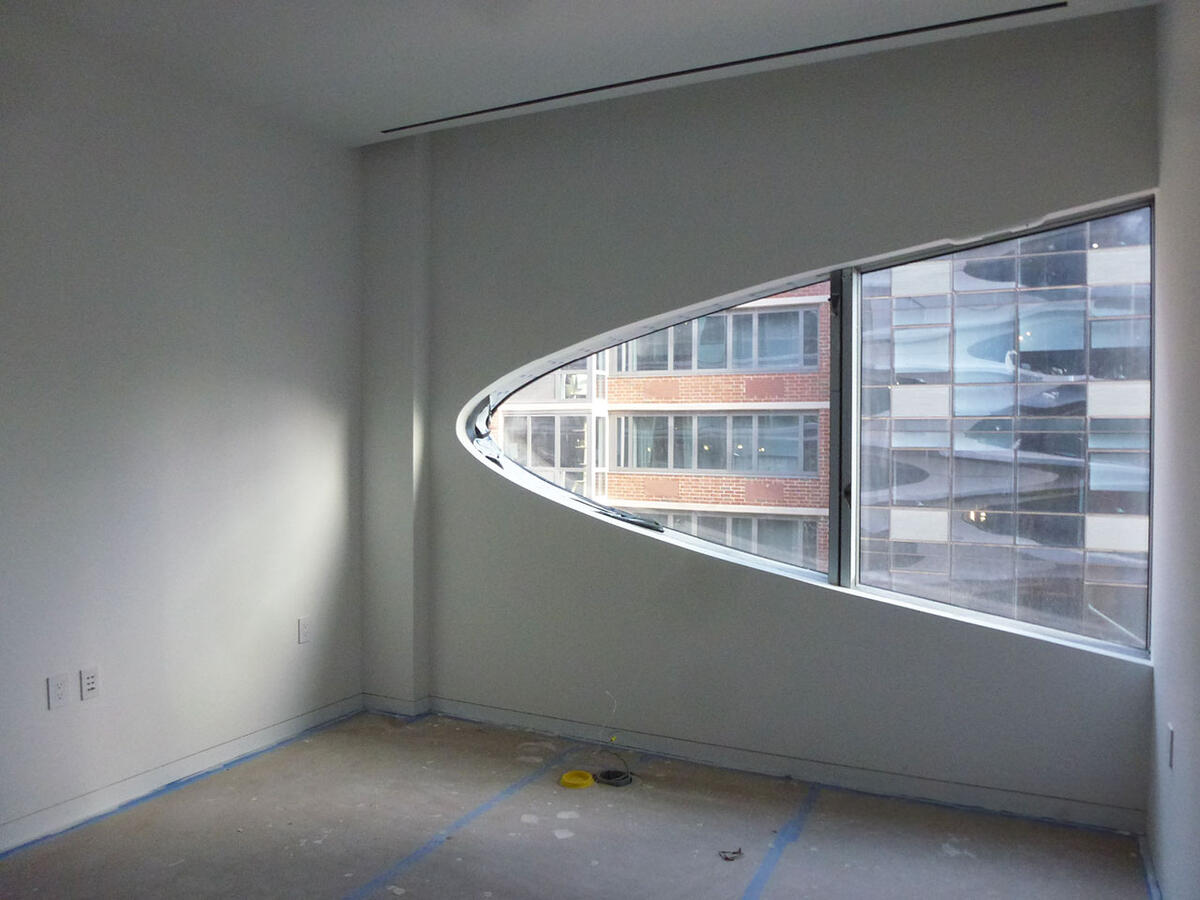 Bathroom stall with wooden paneled floors and a foldable wooden seat